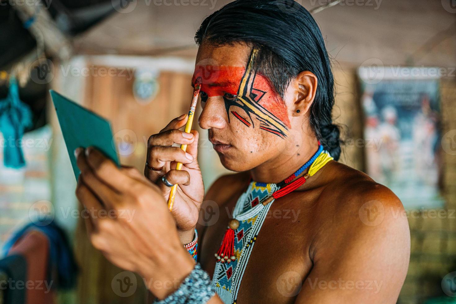 Indian from the Pataxo tribe, using a mirror and doing face painting. photo