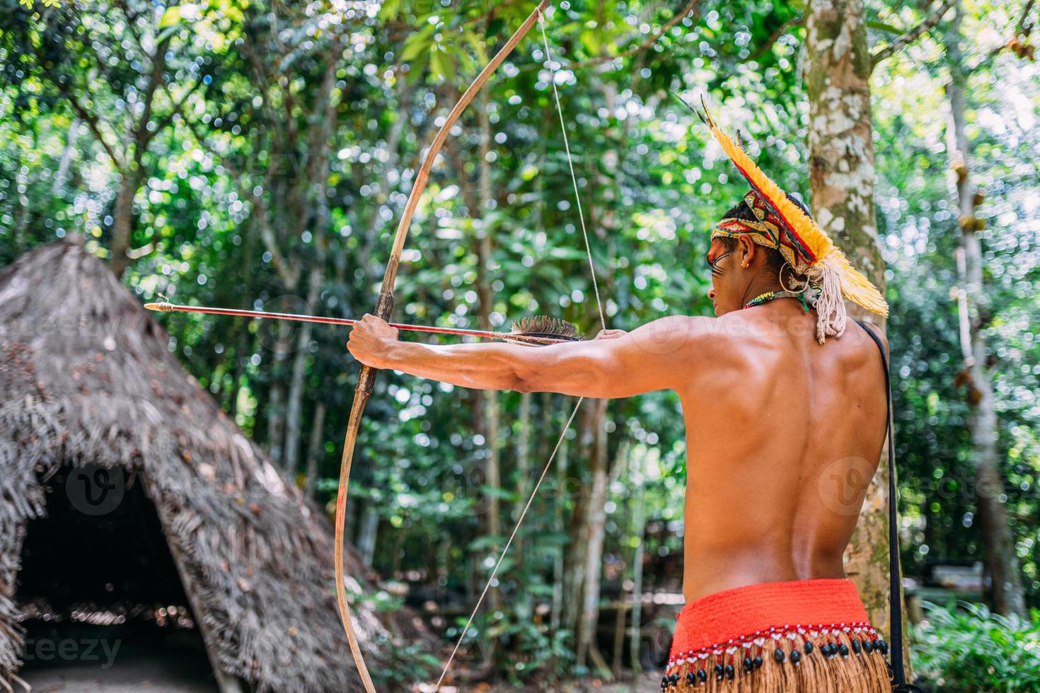 Indian from the Pataxo tribe using a bow and arrow. Brazilian Indian with feather headdress and necklace photo