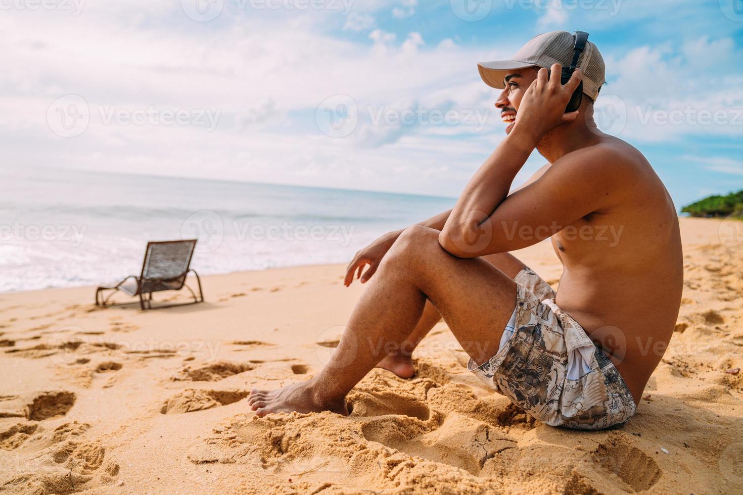 Close up portrait of a latin american man sitting on the sand listening to music photo