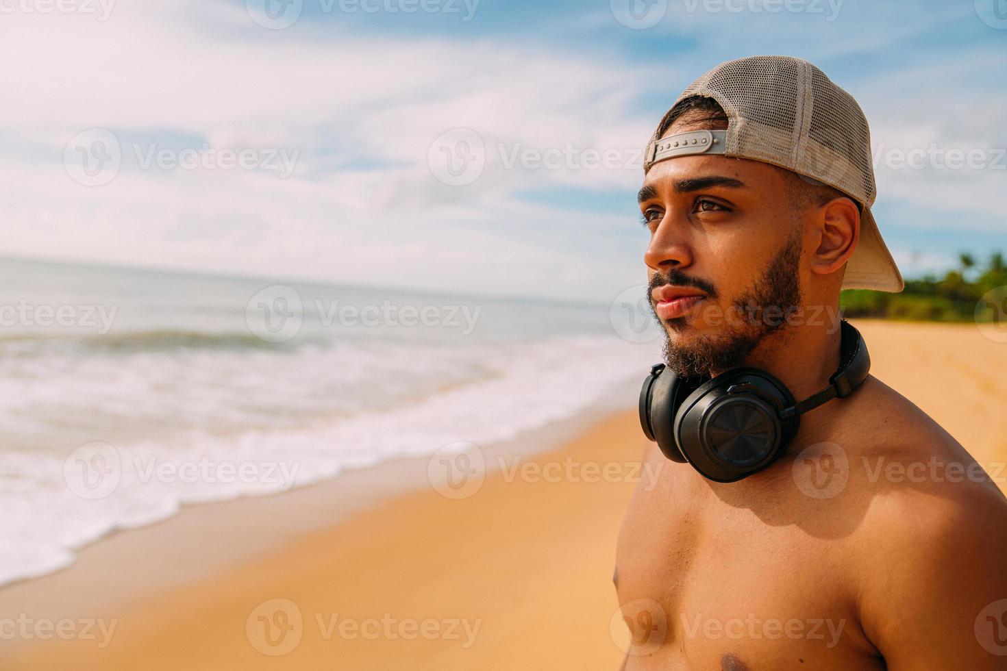 summer holidays, technology and internet concept. latin american man with headset and cap looking to the left photo