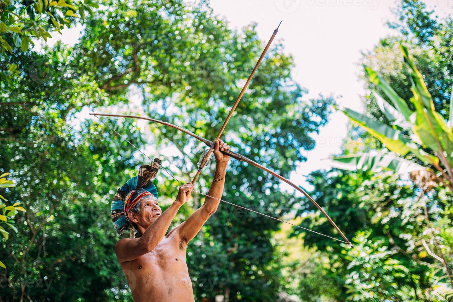 indio de la tribu pataxo, con tocado de plumas y arco y flecha. anciano indio brasileño foto