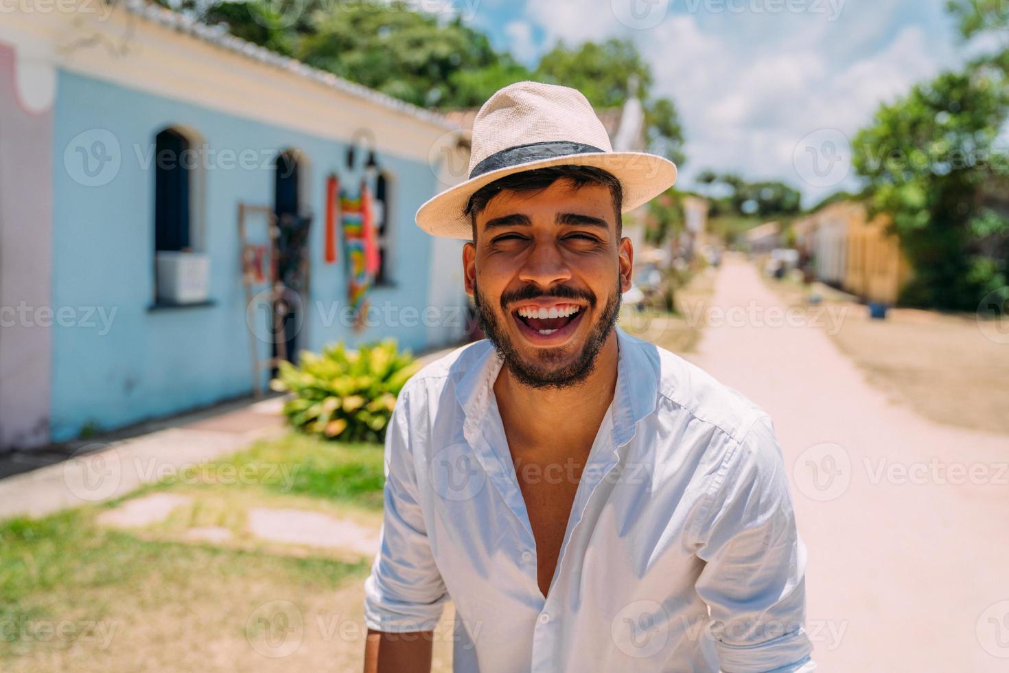 Tourist making selfie in the historic center of Porto Seguro. Latin American man in hat smiling at camera photo