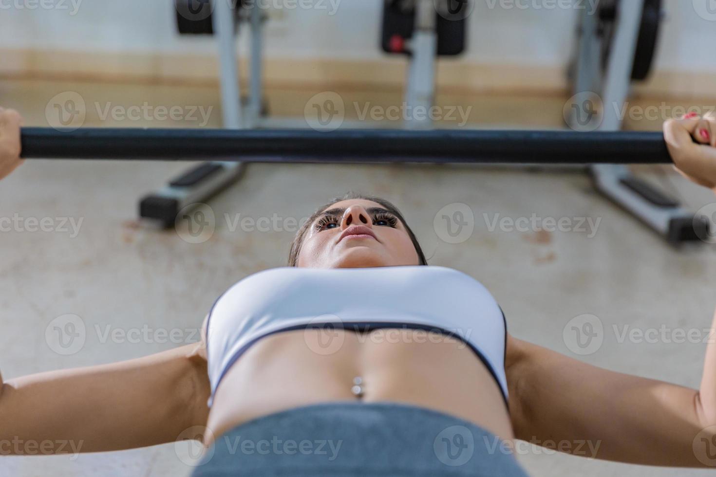 Girl training with bench press in a gym photo