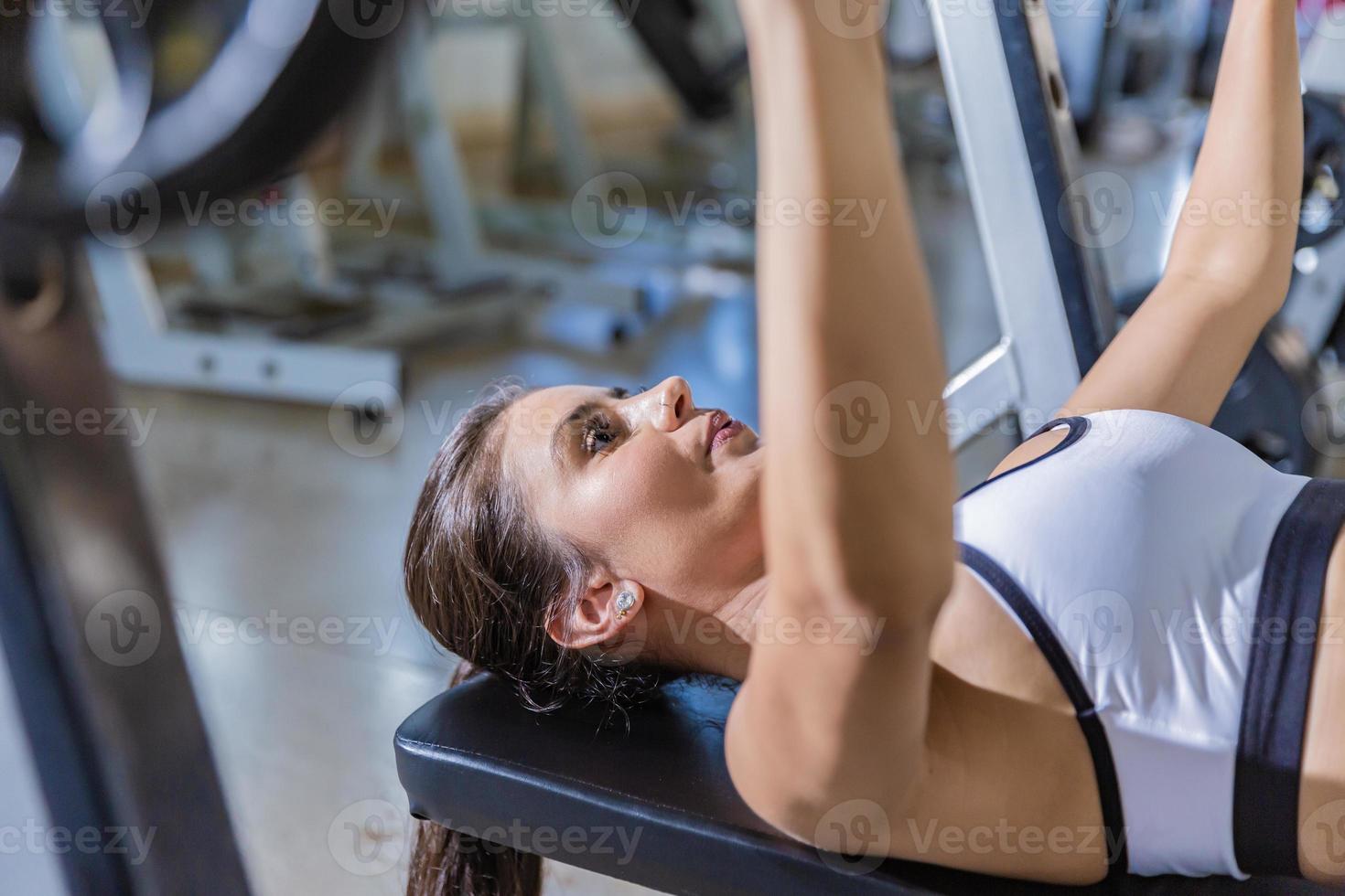 Girl training with bench press in a gym photo