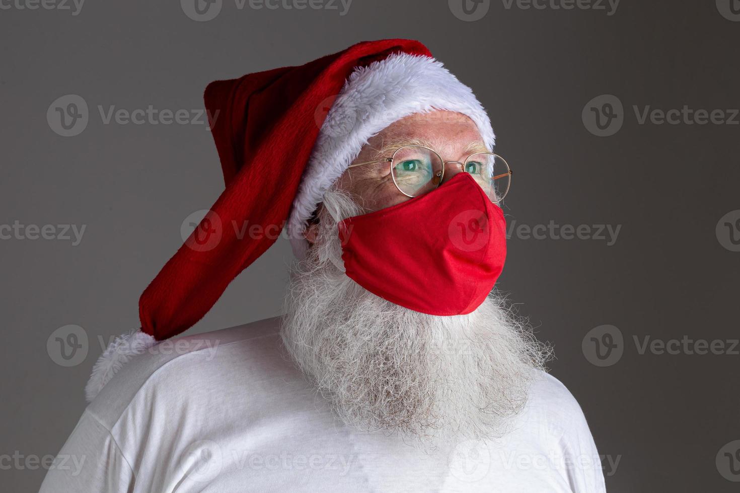 Santa Claus smiles behind red Covid-19 safety face mask. Christmas with social distance. photo