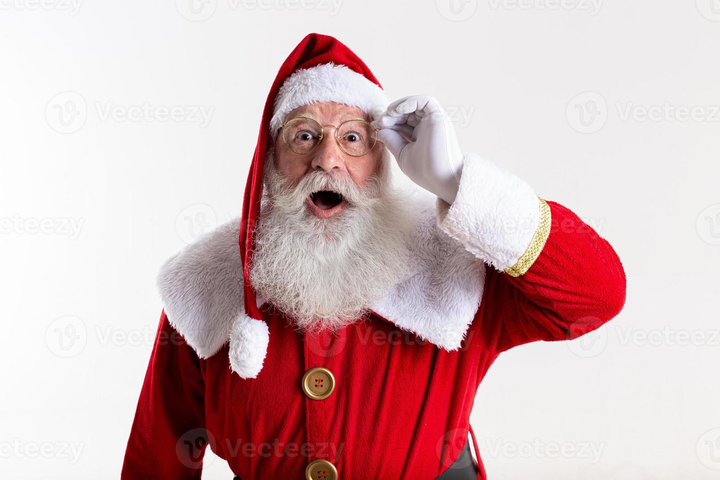 Santa Claus in eyeglasses is looking surprised at camera on white background photo