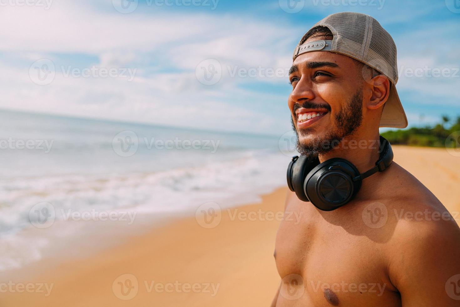 summer holidays, technology and internet concept. smiling latin american man with headset and cap looking to the left photo