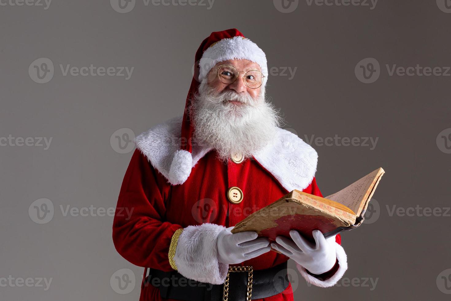 Santa Claus with a old red cover book. Jotting down names gifts for Christmas. Christmas is coming photo