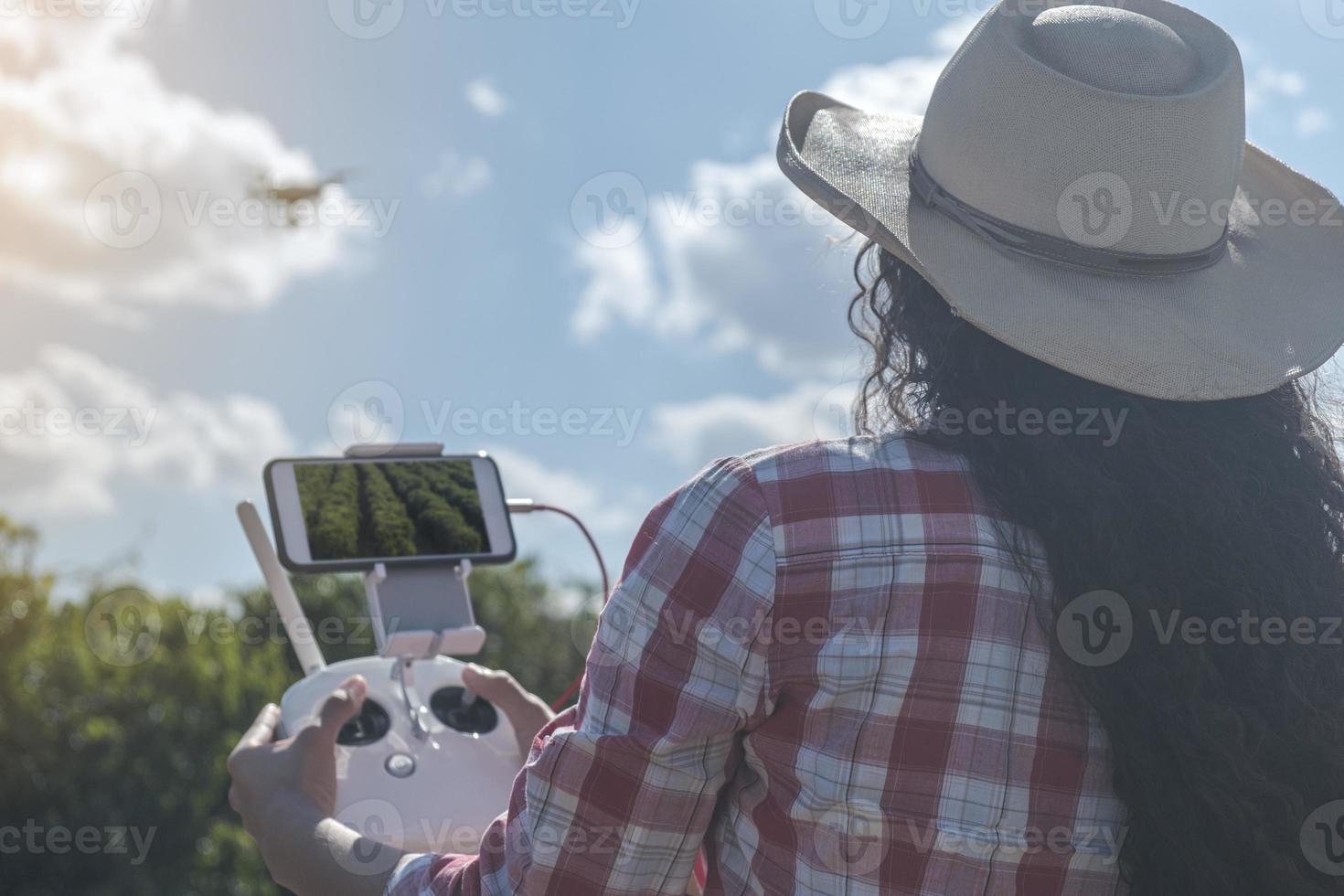 Young woman farmer analyzing a coffee plantation through a drone. Farmer using drone to fly over his coffee plantation. Technology on the farm. photo