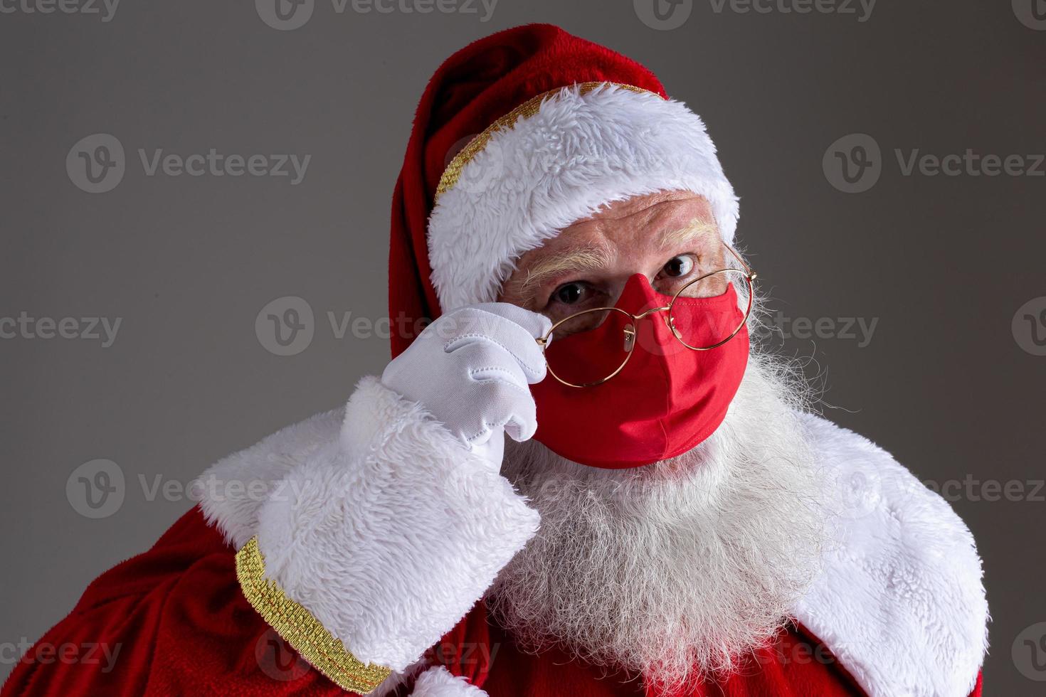 Santa Claus smiles behind red Covid-19 safety face mask. Christmas with social distance. photo