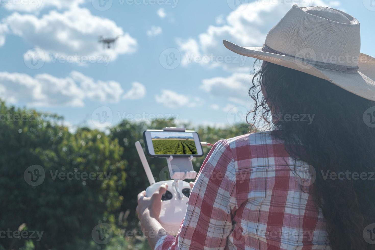 Young woman farmer analyzing a coffee plantation through a drone. Farmer using drone to fly over his coffee plantation. Technology on the farm. photo