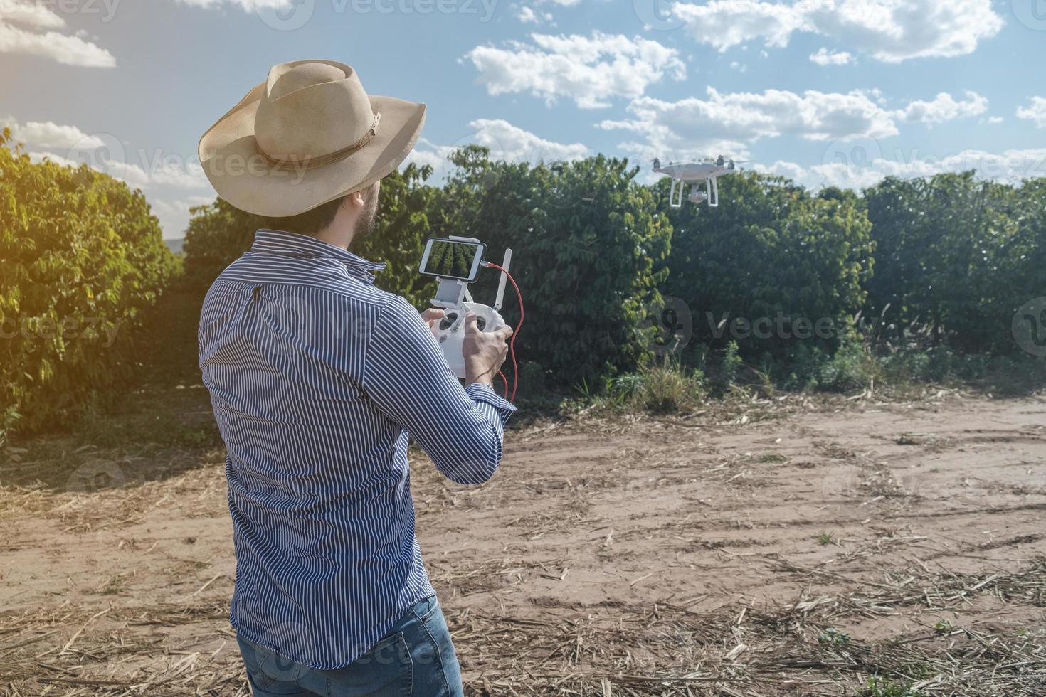 Young farmer analyzing a coffee plantation through a drone. Farmer using drone to fly over his coffee plantation. Technology on the farm. photo