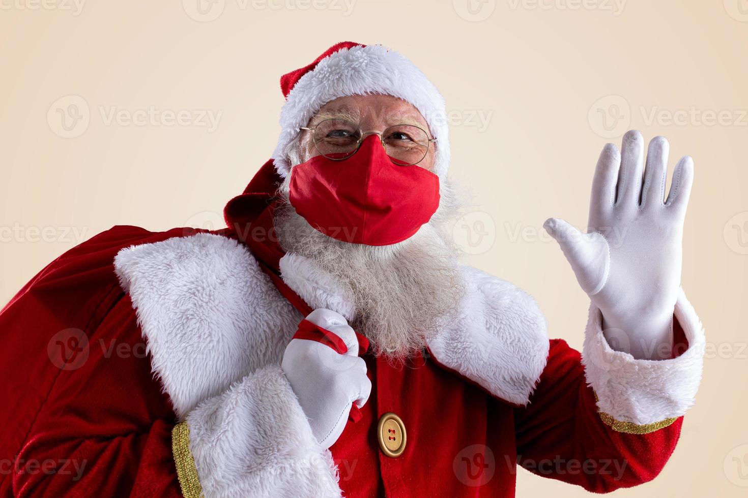 santa claus sonríe detrás de la máscara facial de seguridad roja covid-19. Navidad con distancia social. foto