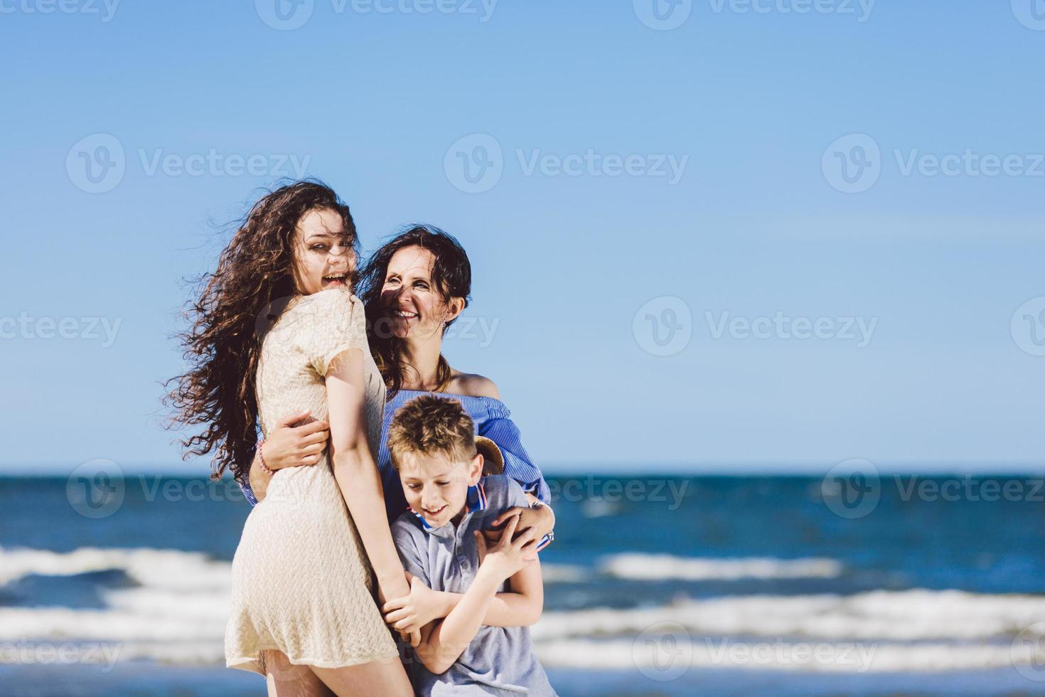 Mother, daughter and son hugging on the beach. photo