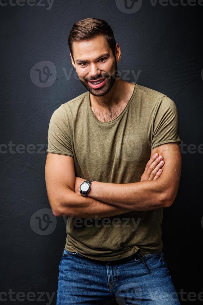 hombre guapo sonriendo, de pie confiado con los brazos cruzados foto