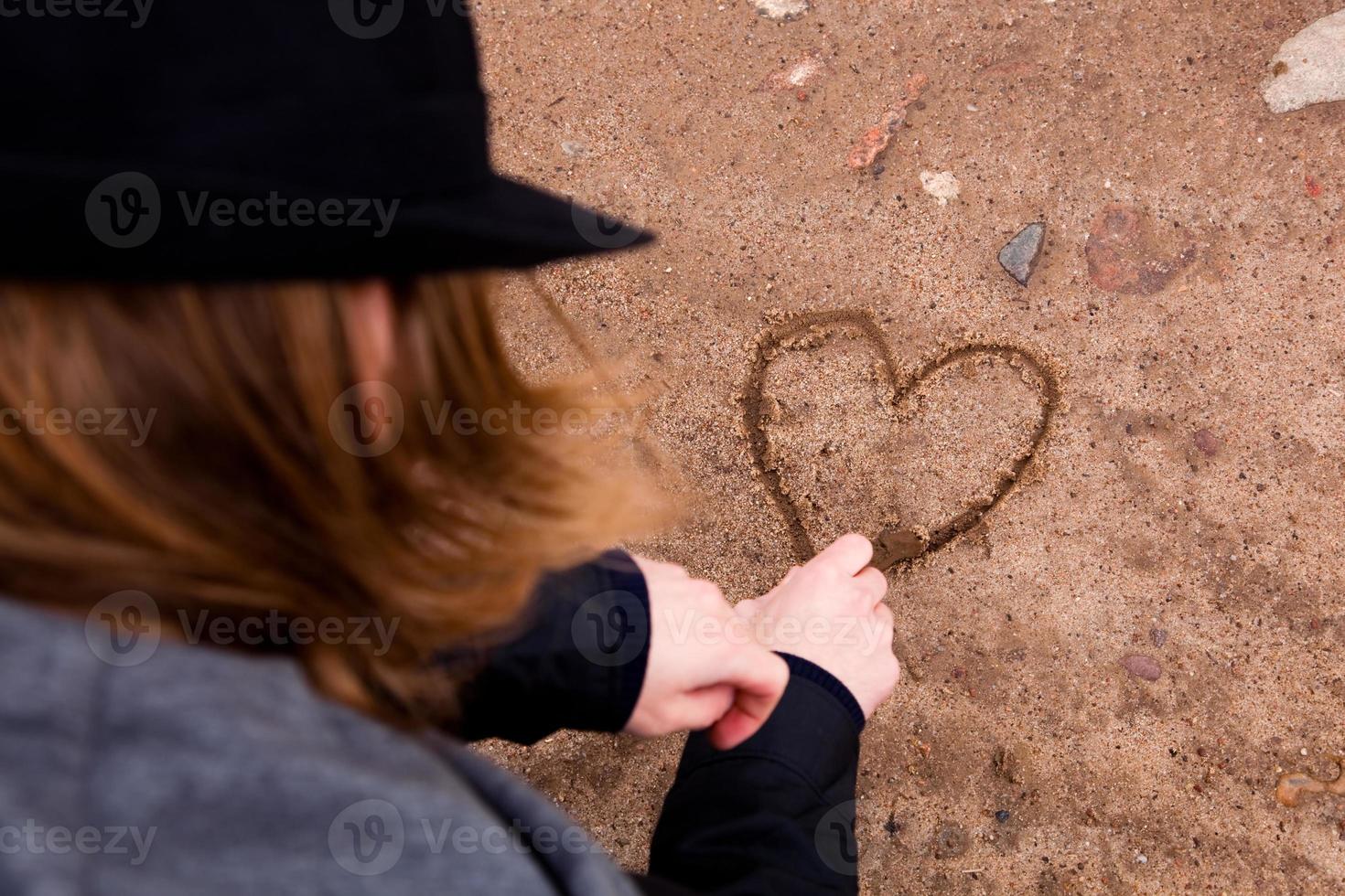 joven dibujando corazón en el suelo foto