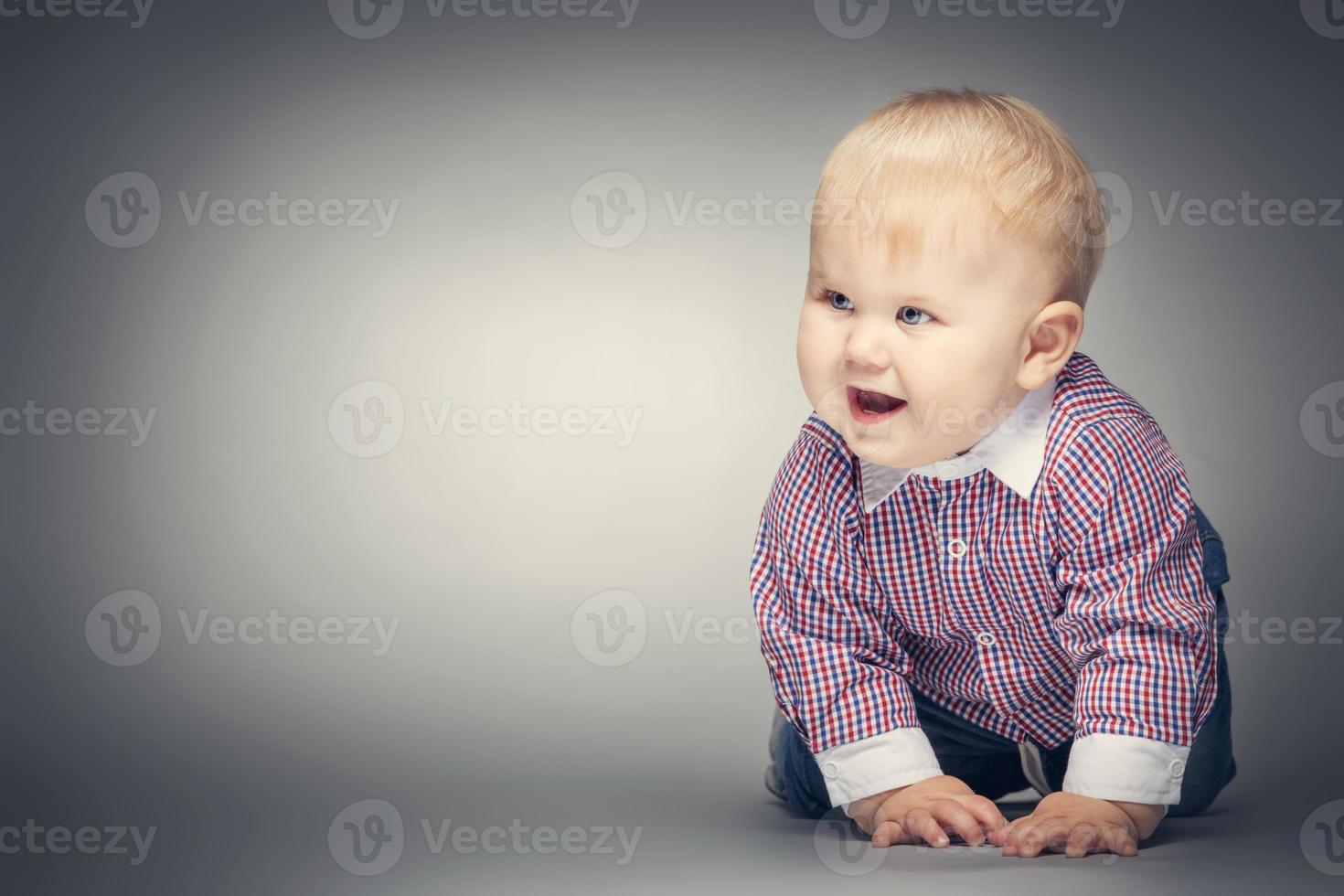 Smiling little boy crawling on the ground. photo