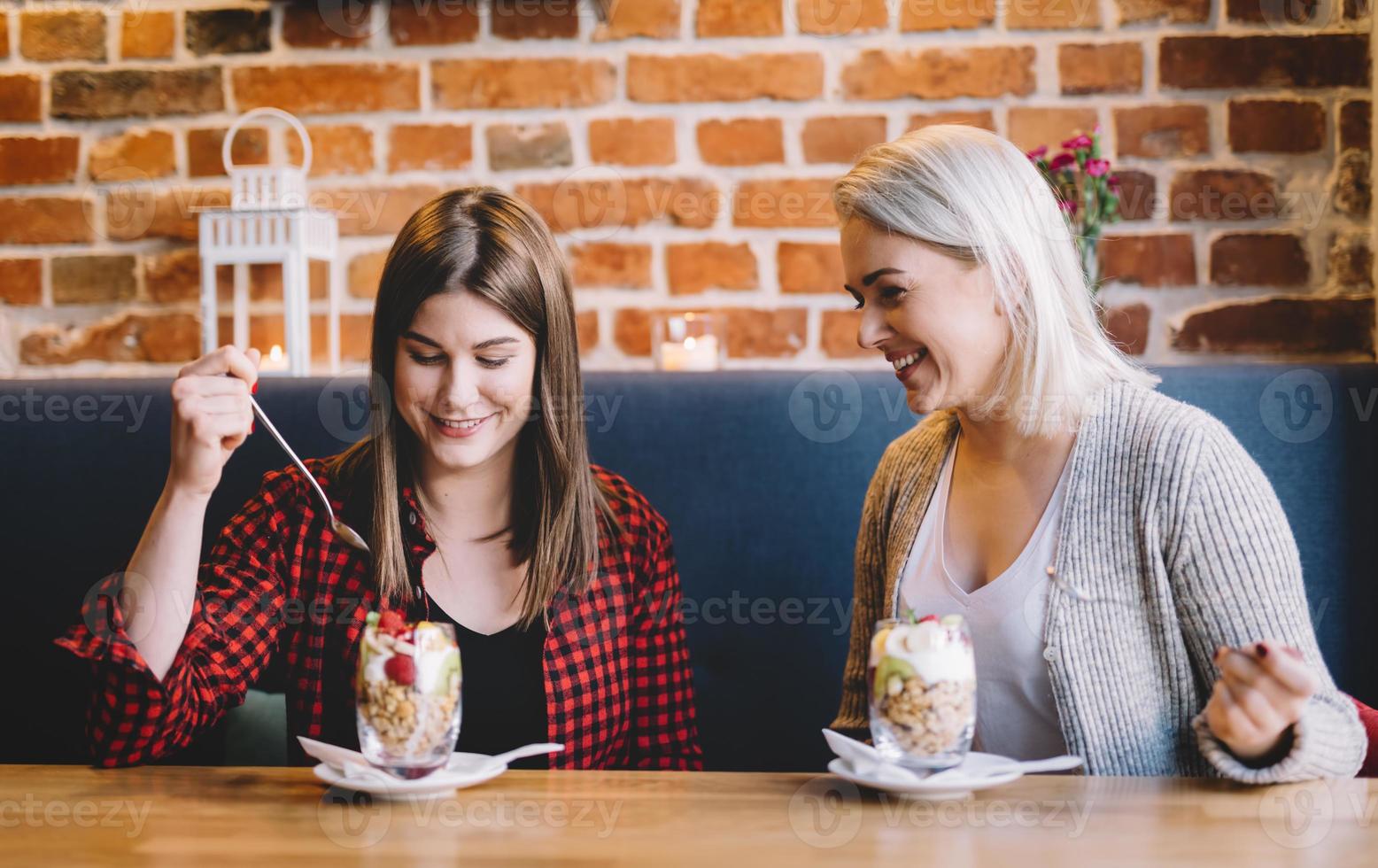 Two women eating healthy snack, chatting. photo