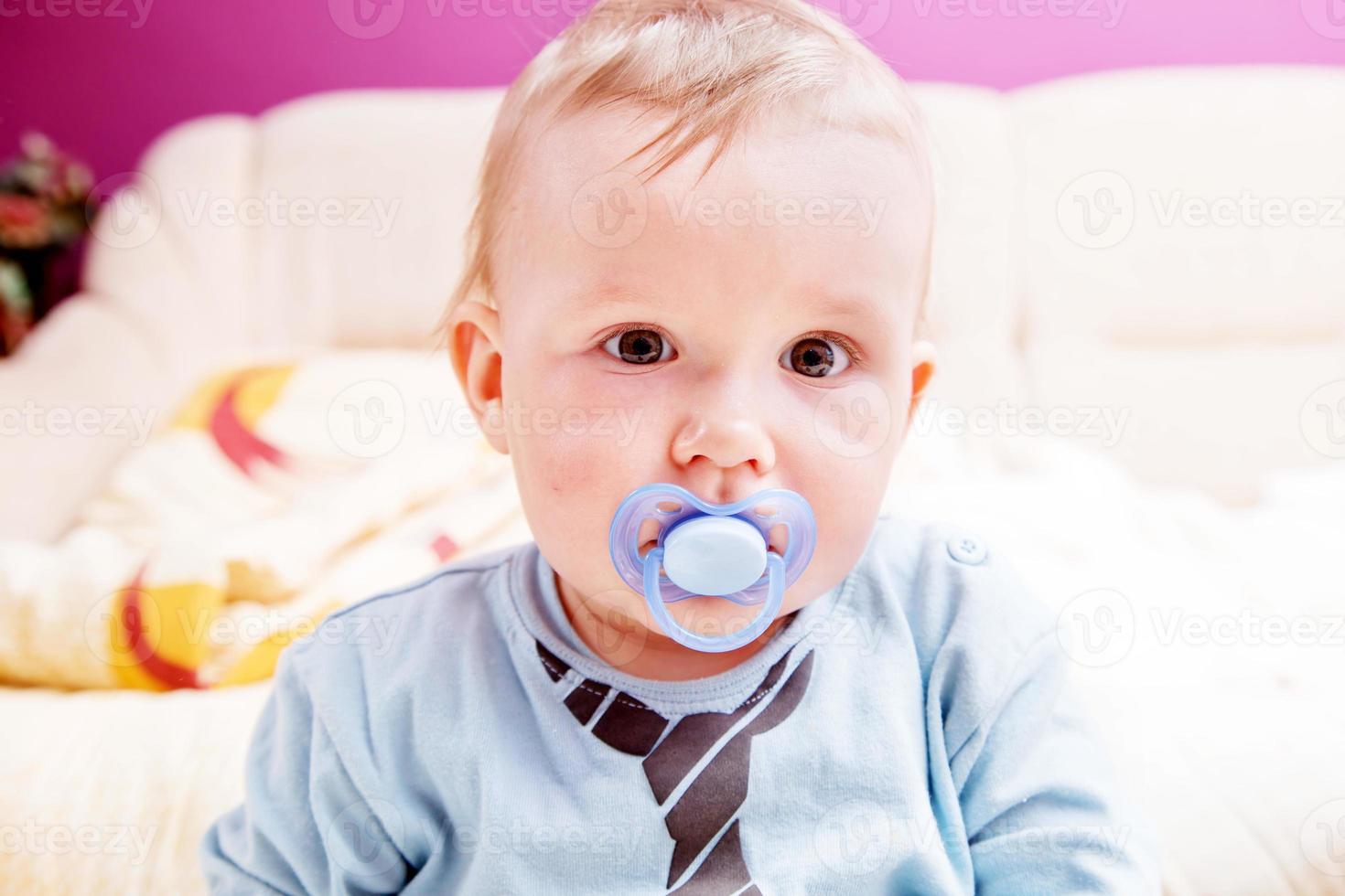 niño pequeño con un maniquí en su boca retrato foto