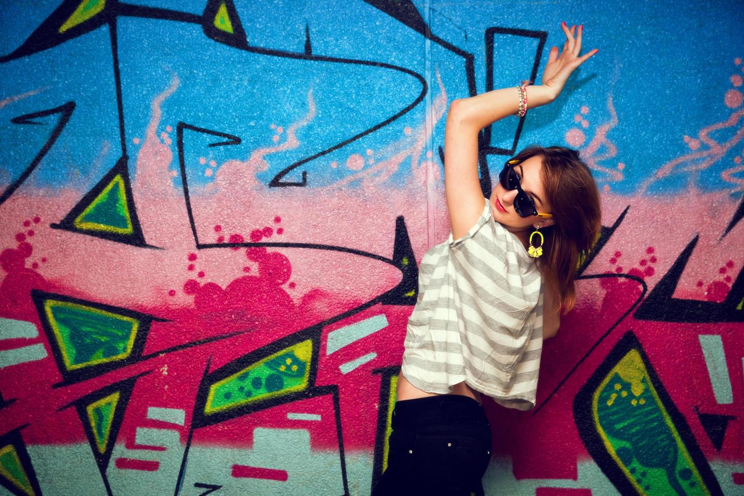 Poland, 2022 - Stylish girl in a dance pose against graffiti wall photo