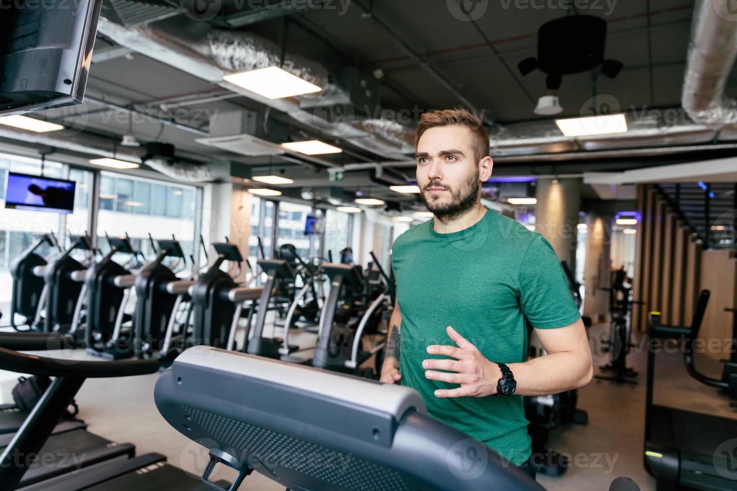 Man in his 30s running on a treadmill. photo
