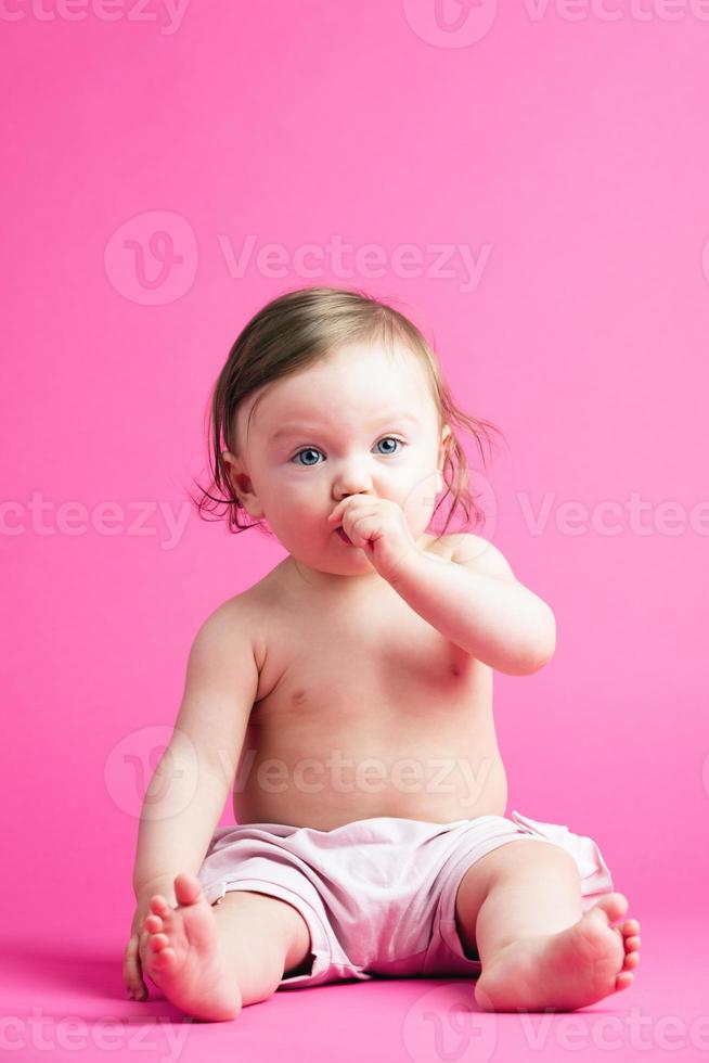 Baby girl putting her hand into her mouth. photo