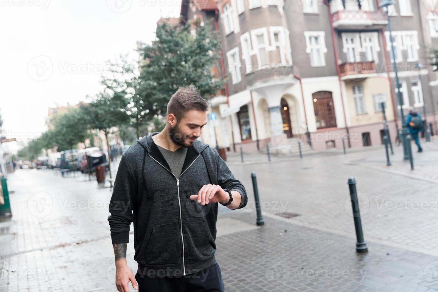 Casual man looking at his watch on the street photo