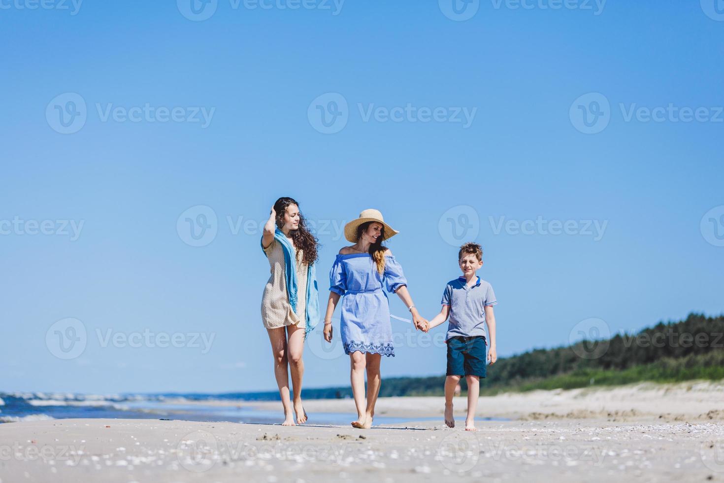 Mother and her two children walking on the beach photo