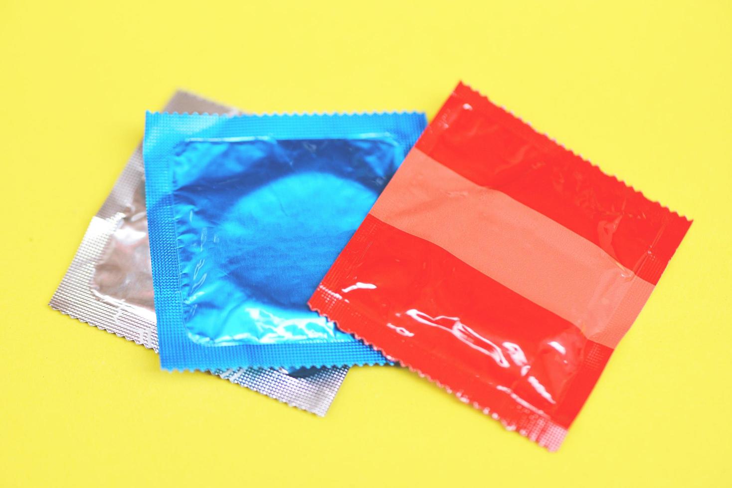 Condom isolated on yellow background - Colorful condom pack for birth control contraceptive means prevent pregnancy or sexually transmitted disease photo