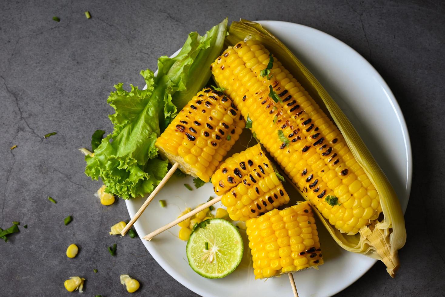 maíz dulce cocinado en un plato blanco, comida de maíz dulce con ensalada de verduras, lima, cilantro y lechuga, mazorcas de maíz maduras, maíz dulce a la parrilla para comida, cena vegana o merienda foto