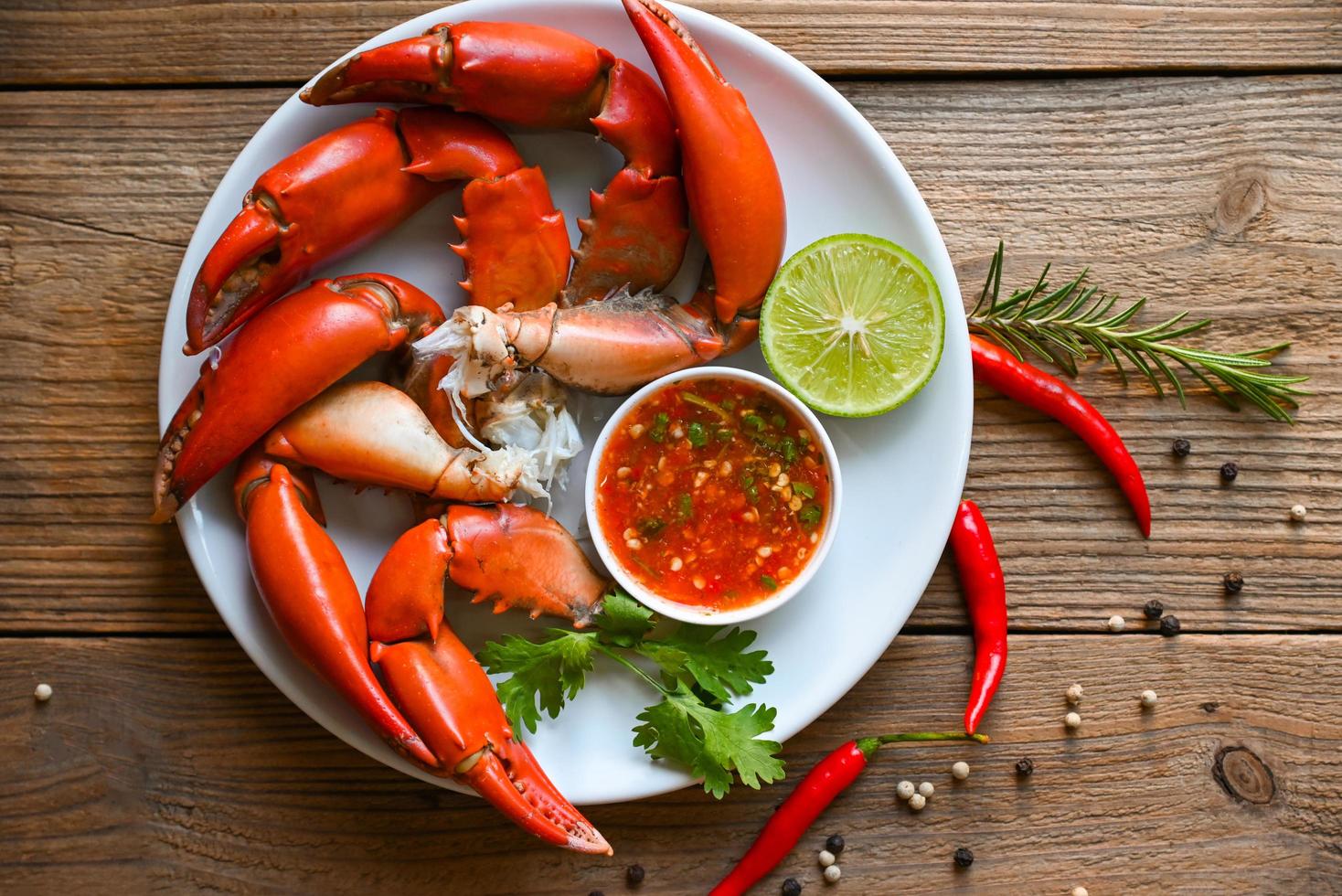 fresh crab on white plate, claw crab cooking food seafood plate with lemon lime, boiled or steamed crab red in the restaurant - top view photo