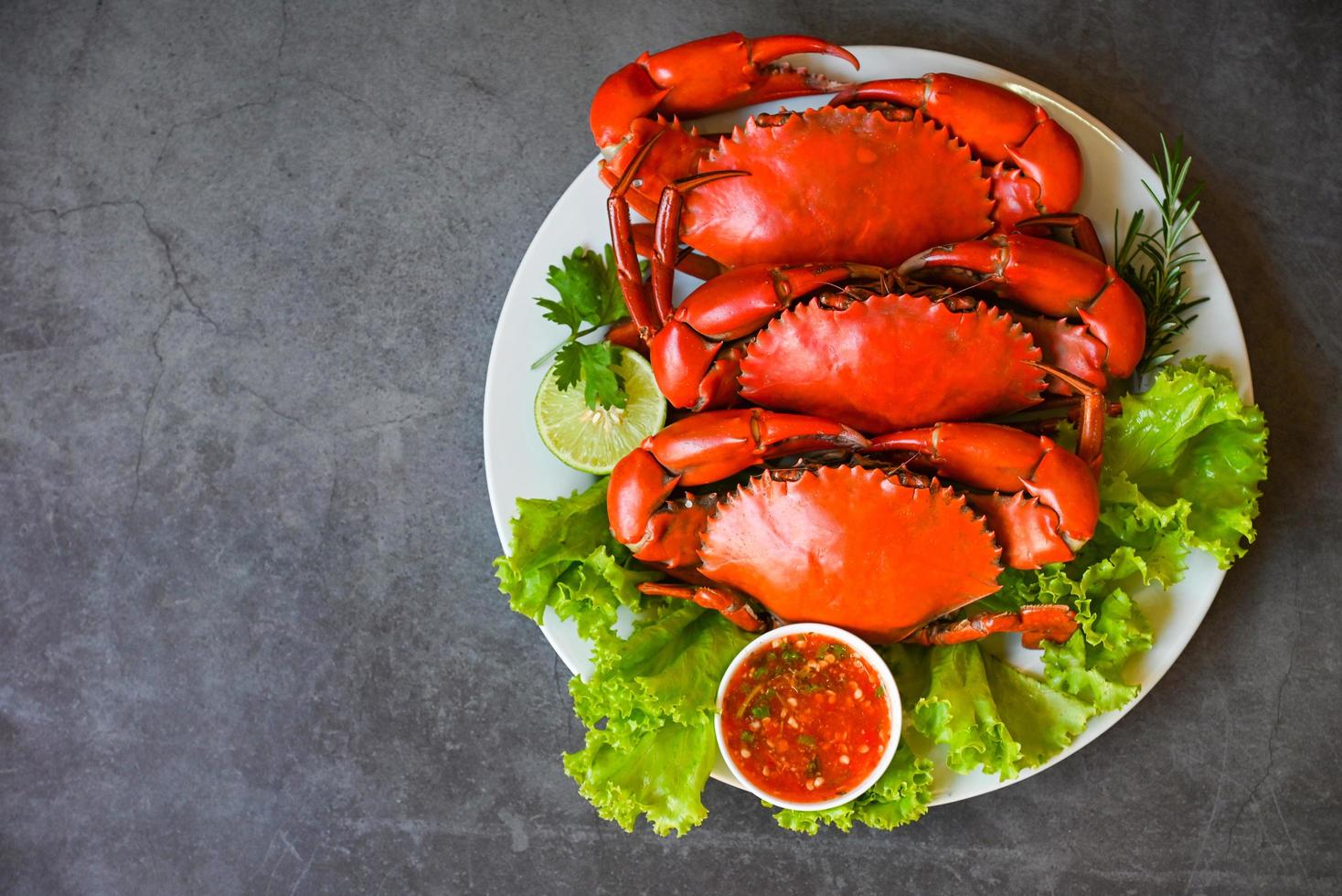 fresh crab on white plate and seafood sauce, crab cooking food boiled or steamed crab red in the restaurant, seafood plate with herbs spices rosemary lemon lime salad lettuce vegetable photo