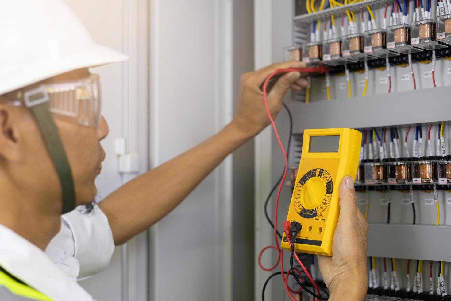 Electrician engineer work tester measuring voltage and current of power electric line in electical cabinet control. photo