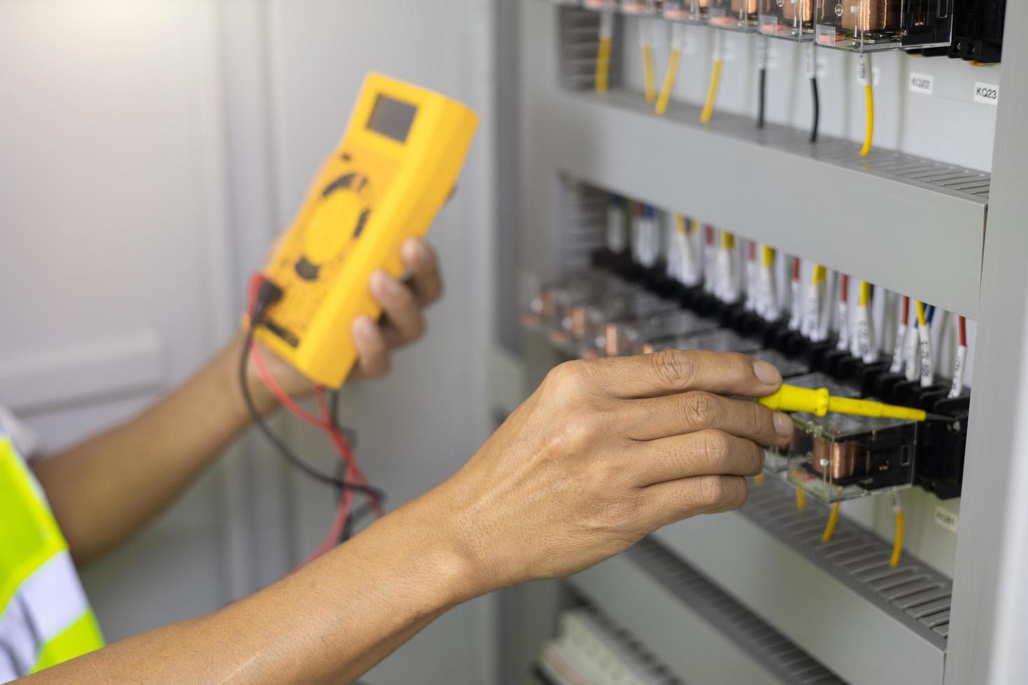 Electrician engineer work tester measuring voltage and current of power electric line in electical cabinet control. photo