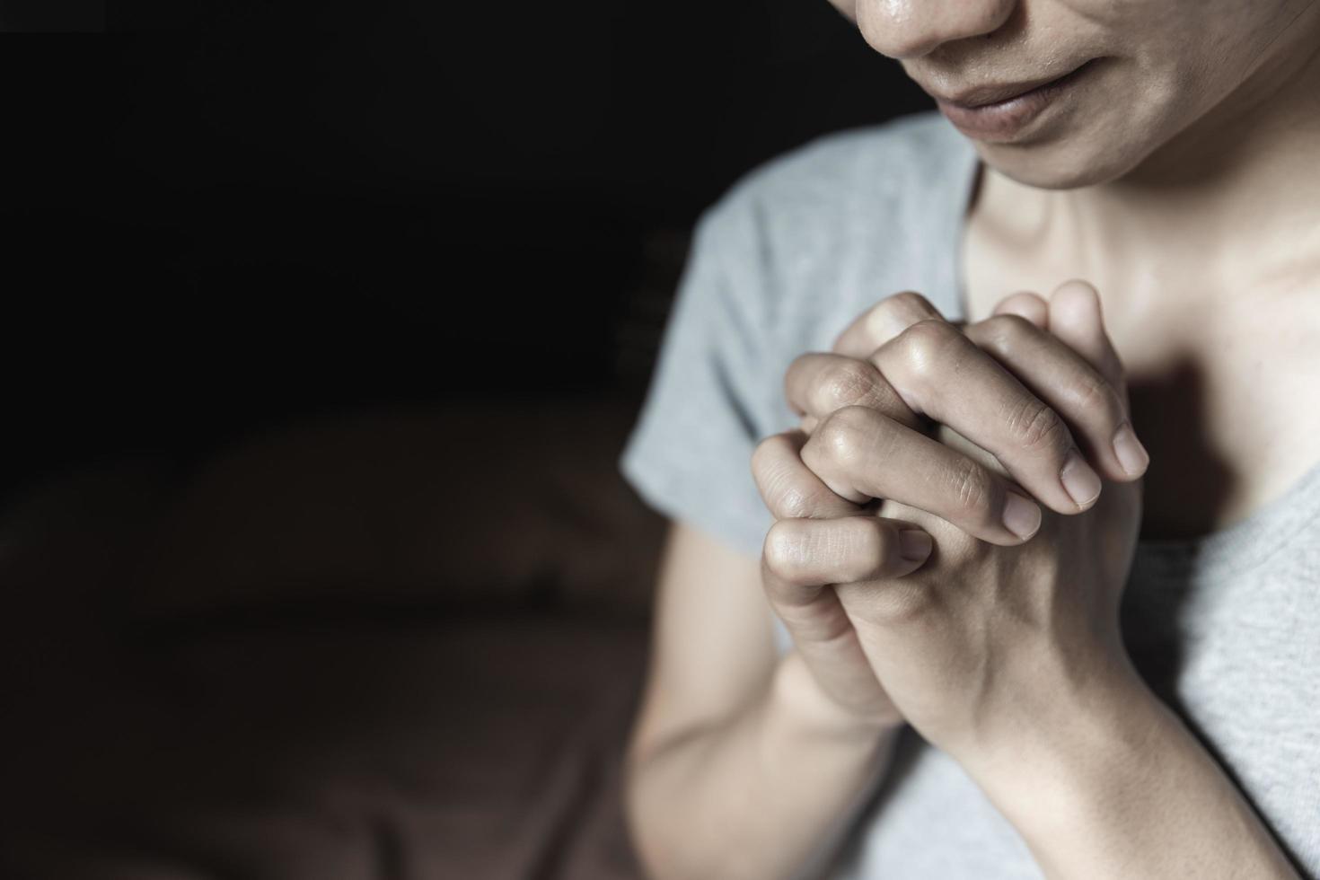 mano de mujer mientras reza por la religión cristiana, mujer casual rezando con las manos juntas para pensar en un dios amoroso, alabamos a dios. foto