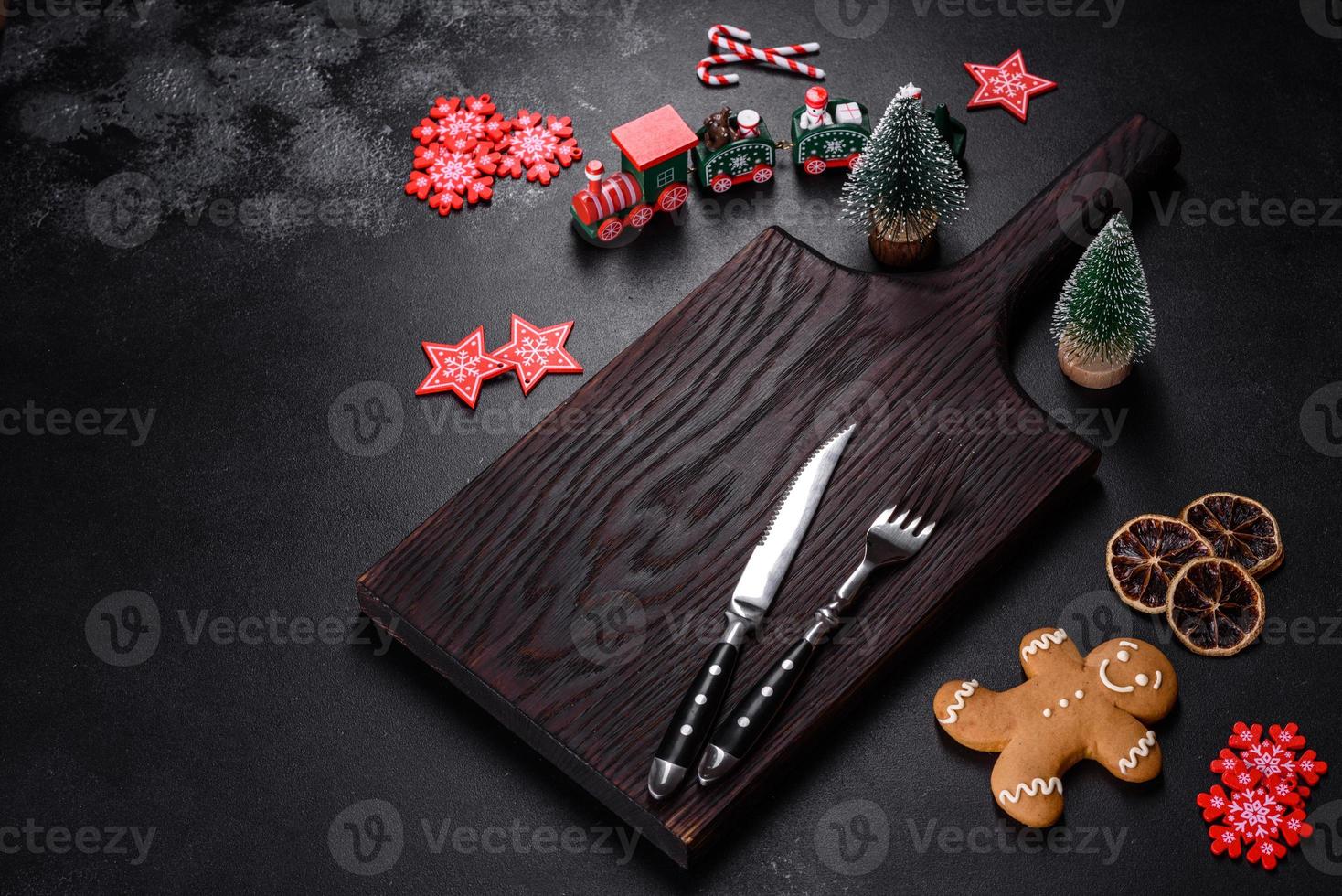 Christmas homemade gingerbread cookies, spices and cutting board on dark background photo