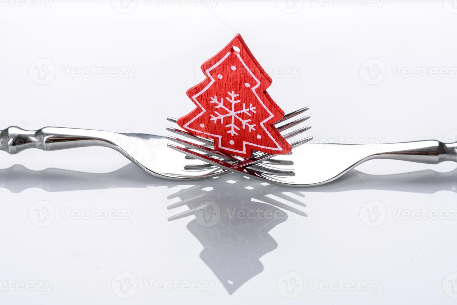 A small Christmas tree decoration on two forks on a white background photo