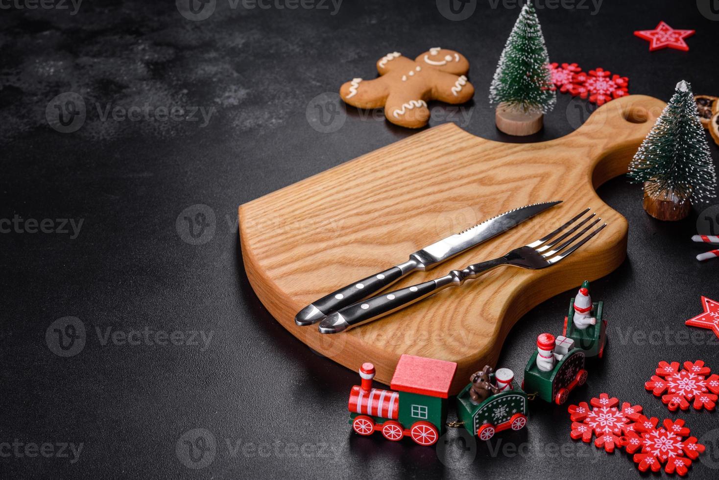 Christmas homemade gingerbread cookies, spices and cutting board on dark background photo