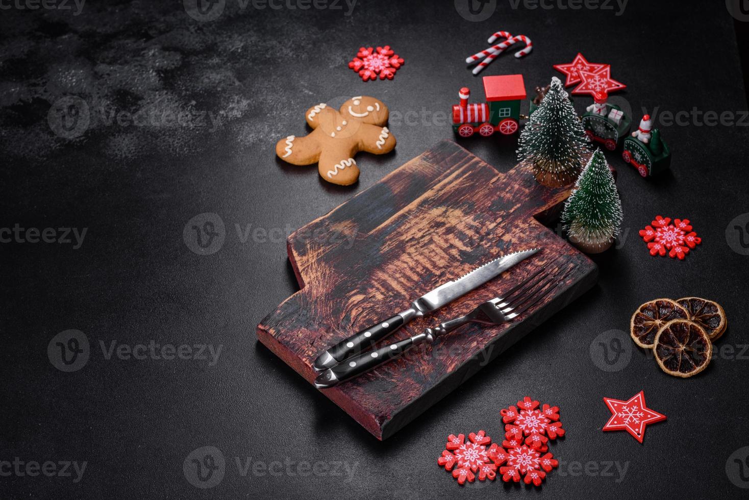 Christmas homemade gingerbread cookies, spices and cutting board on dark background photo