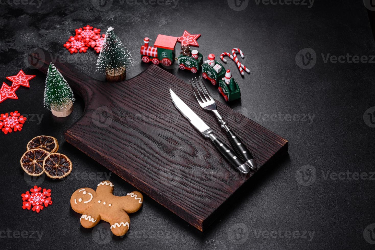 Christmas homemade gingerbread cookies, spices and cutting board on dark background photo
