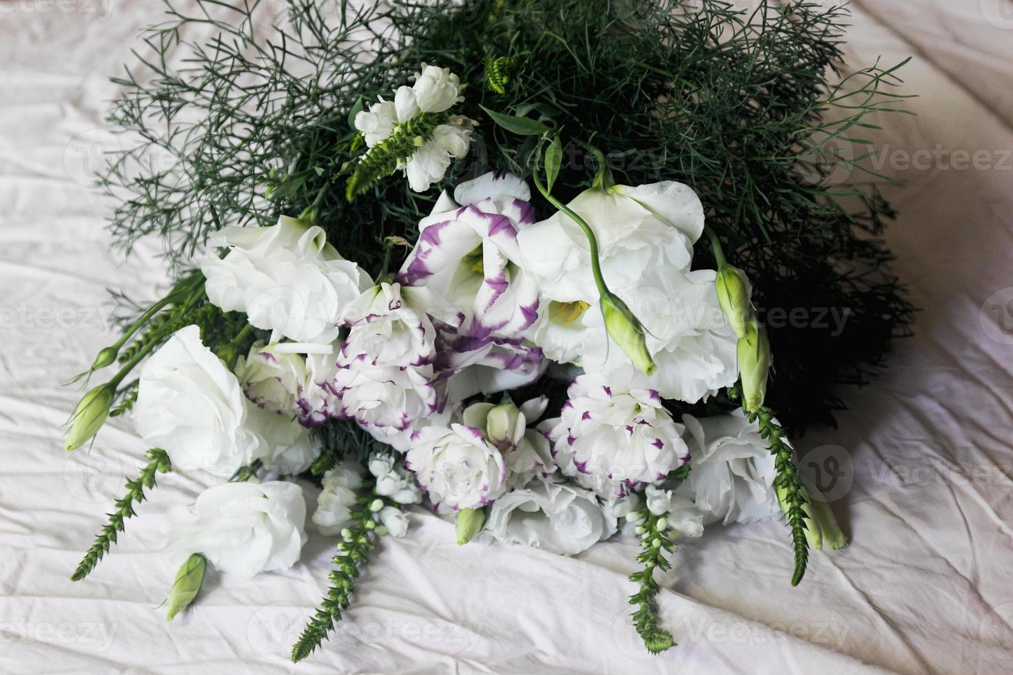 White bouquet of flowers on a white background, against the background of bed linen, a bouquet of green color, background, white beautiful flowers photo