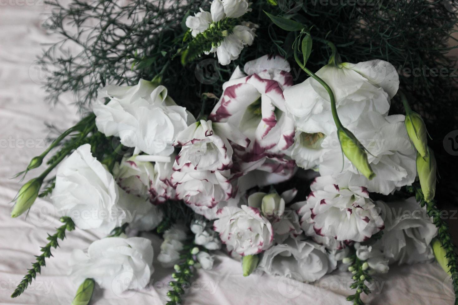 White bouquet of flowers on a white background, against the background of bed linen, a bouquet of green color, background, white beautiful flowers photo
