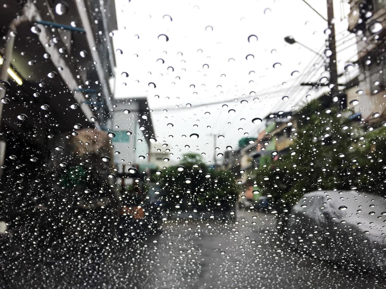 Water drops on a window in the rain. View of car on the street. photo