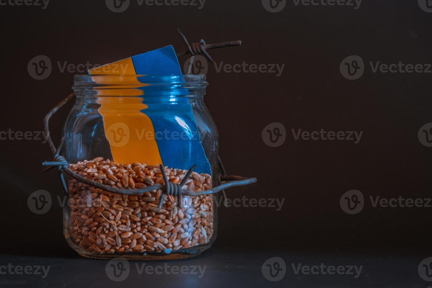 Wheat grain in a jar around barbed wire, the concept of sanctions and the crisis in Ukraine, Problems with Ukraine grain, the blockade of Ukraine grain. photo