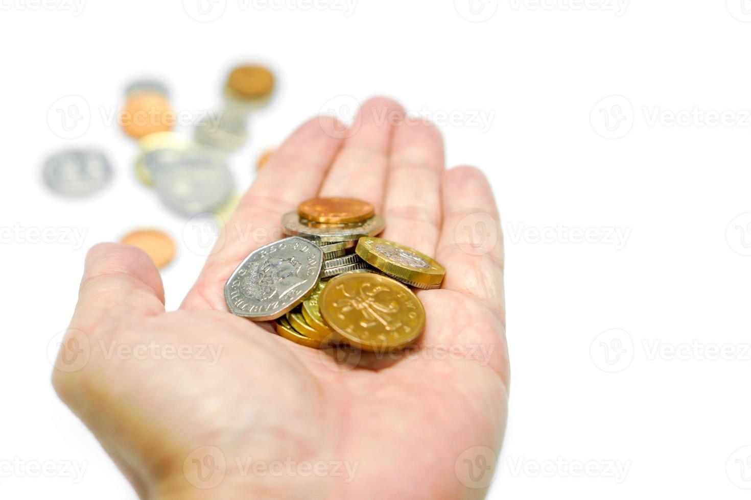 monedas de moneda británica en la mano y monedas borrosas con aislamiento sobre fondo blanco y hacer con caminos. foto