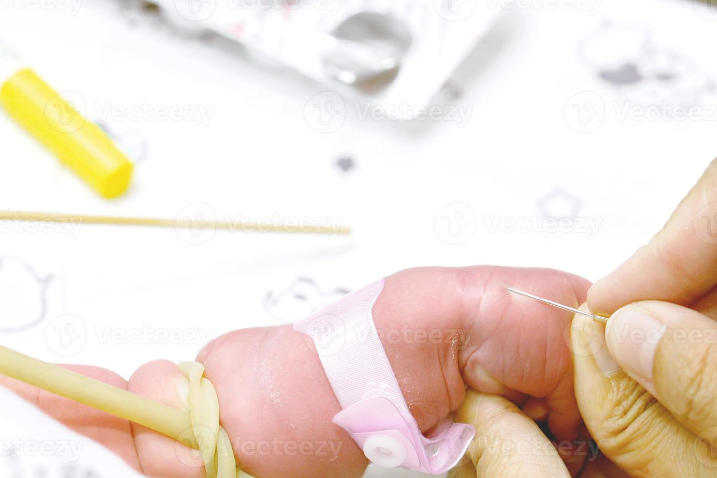 Closeup of nurse hands uses gradually stabbing medical needles at sick baby's hands to prepare fill the saline solution and medicine for the be severely sick newborn. photo