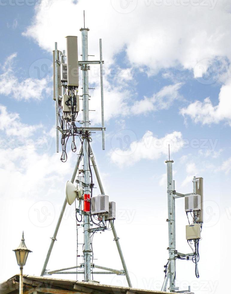 Communication tower with antennas on the top of building and bright blue sky background. photo