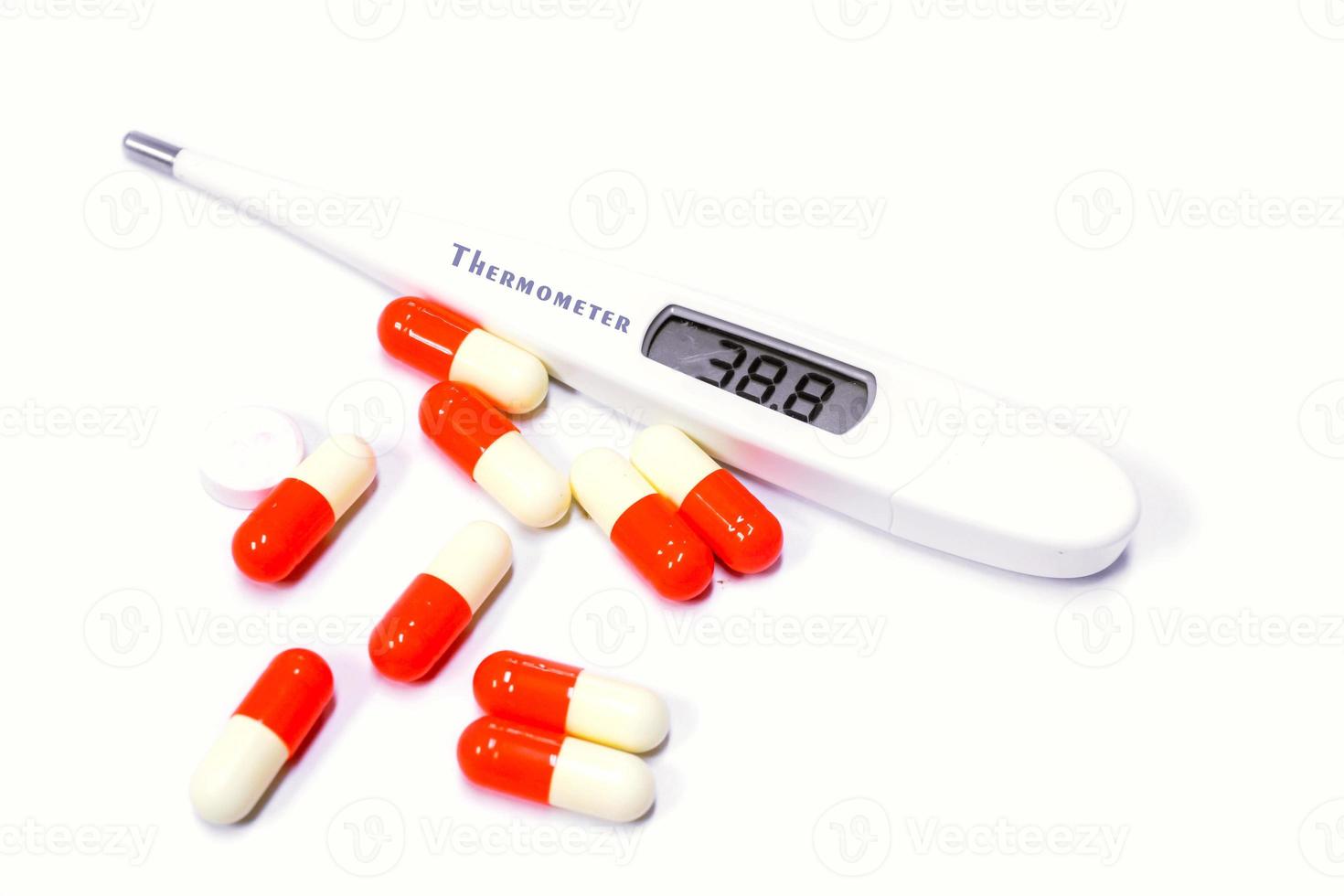 Capsule medicine of drug and electric medical thermometer on white background. photo