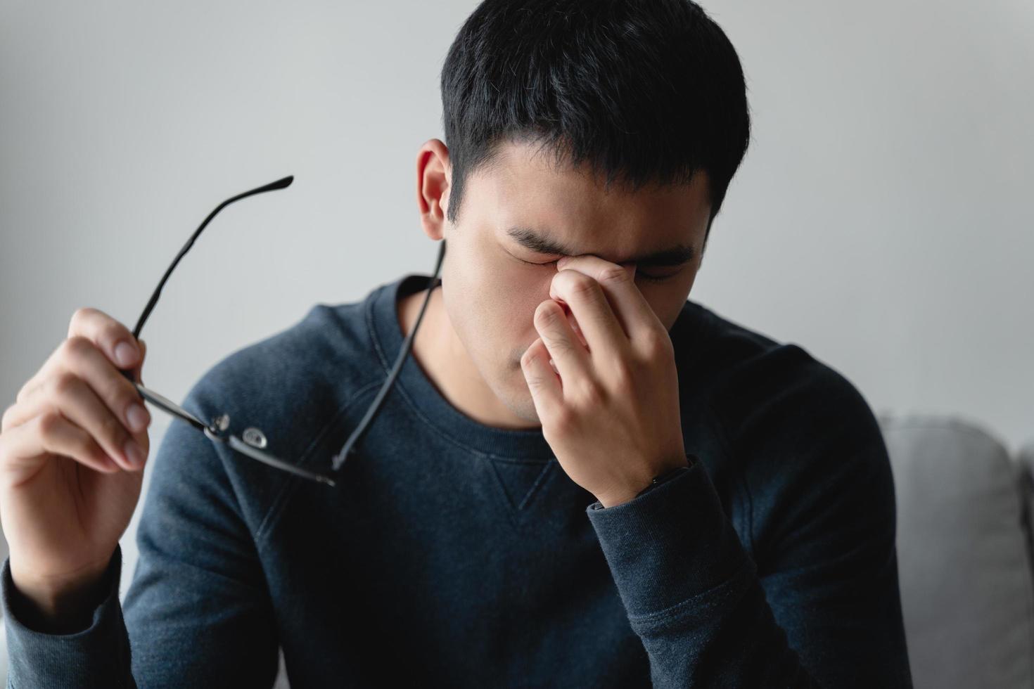 stressed man take off glasses massage eyes feel fatigue suffering from headache, exhausted man having eyestrain or astigmatism with overwork. photo