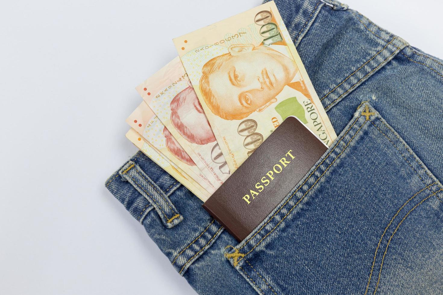 Close up Singapore dollars with passport  in a jeans pocket isolated on white background, clipping path photo